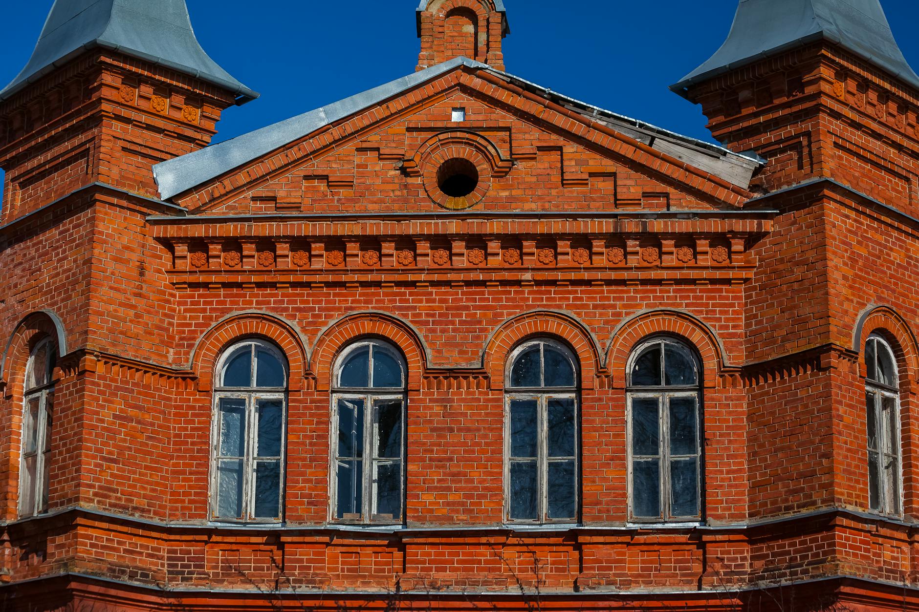 Kamień elewacyjny czy płytki klinkierowe: co lepsze w polskim klimacie Czerwona ceglana elewacja z łukowymi oknami i detalami architektonicznymi