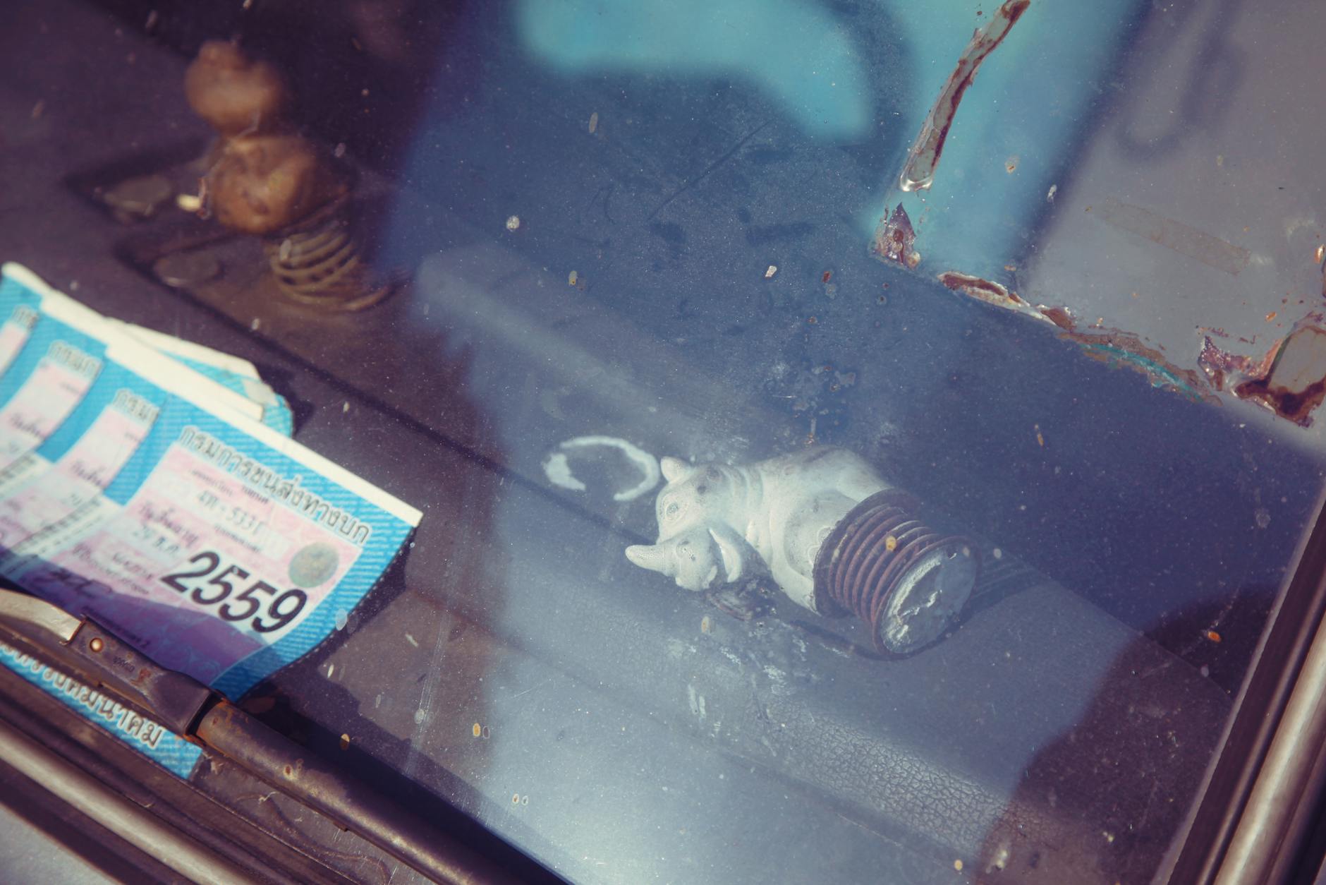 Dokumenty z pozwoleniem na budowę i figurka nosorożca za szybą samochodu Dokumenty z pozwoleniem na budowę i figurka nosorożca za szybą samochodu