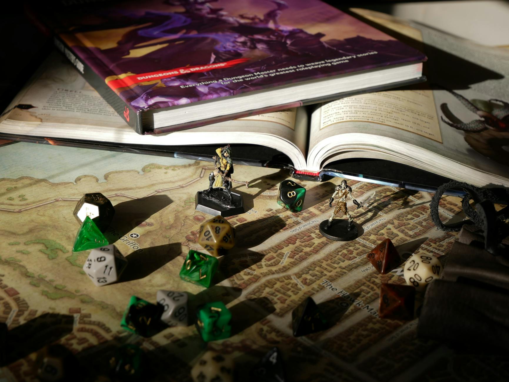 Zbliżenie na stół RPG z mapą, podręcznikami, kośćmi i figurkami