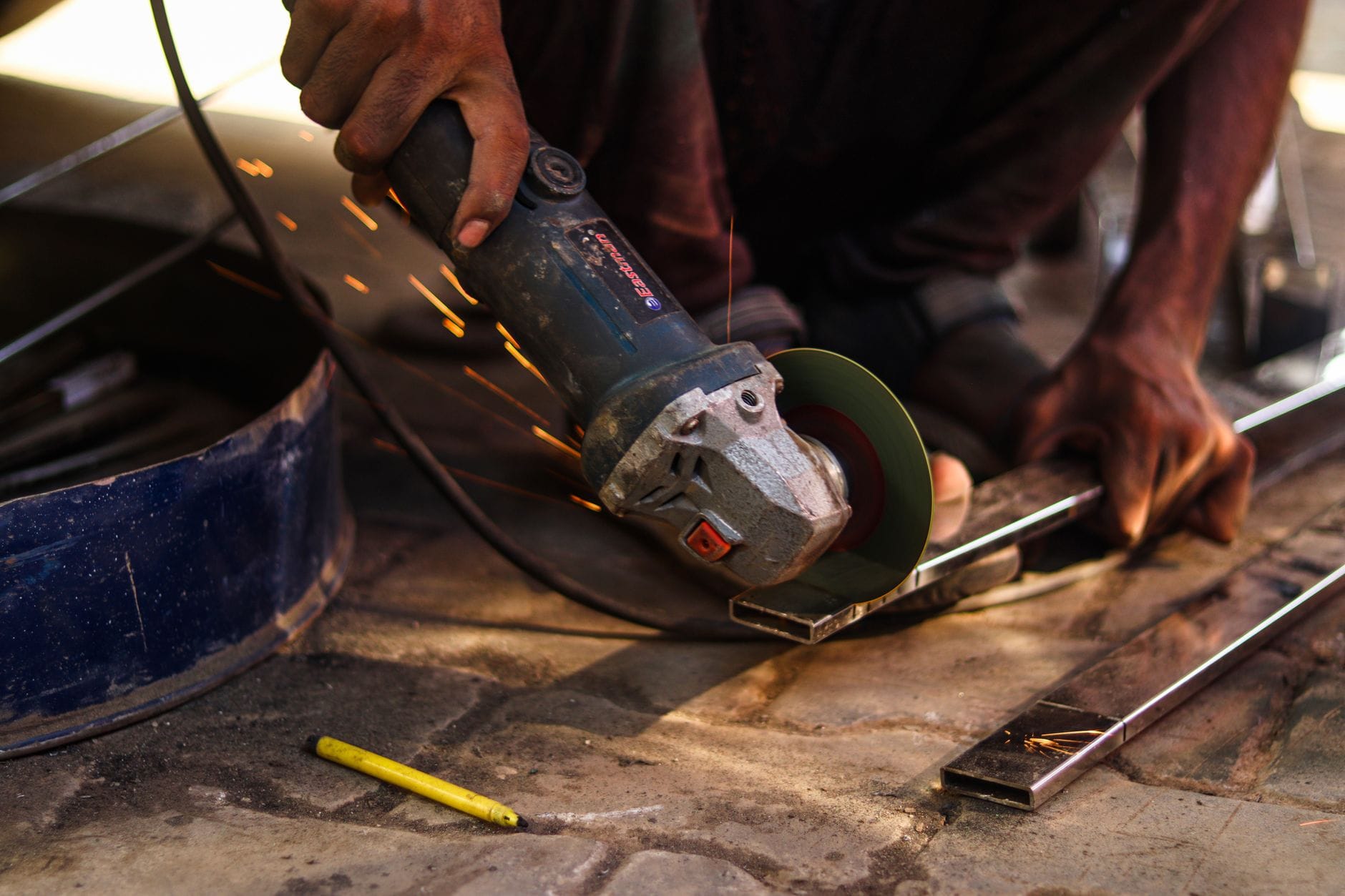Pracownik tnie metal szlifierką kątową, wylatują iskry