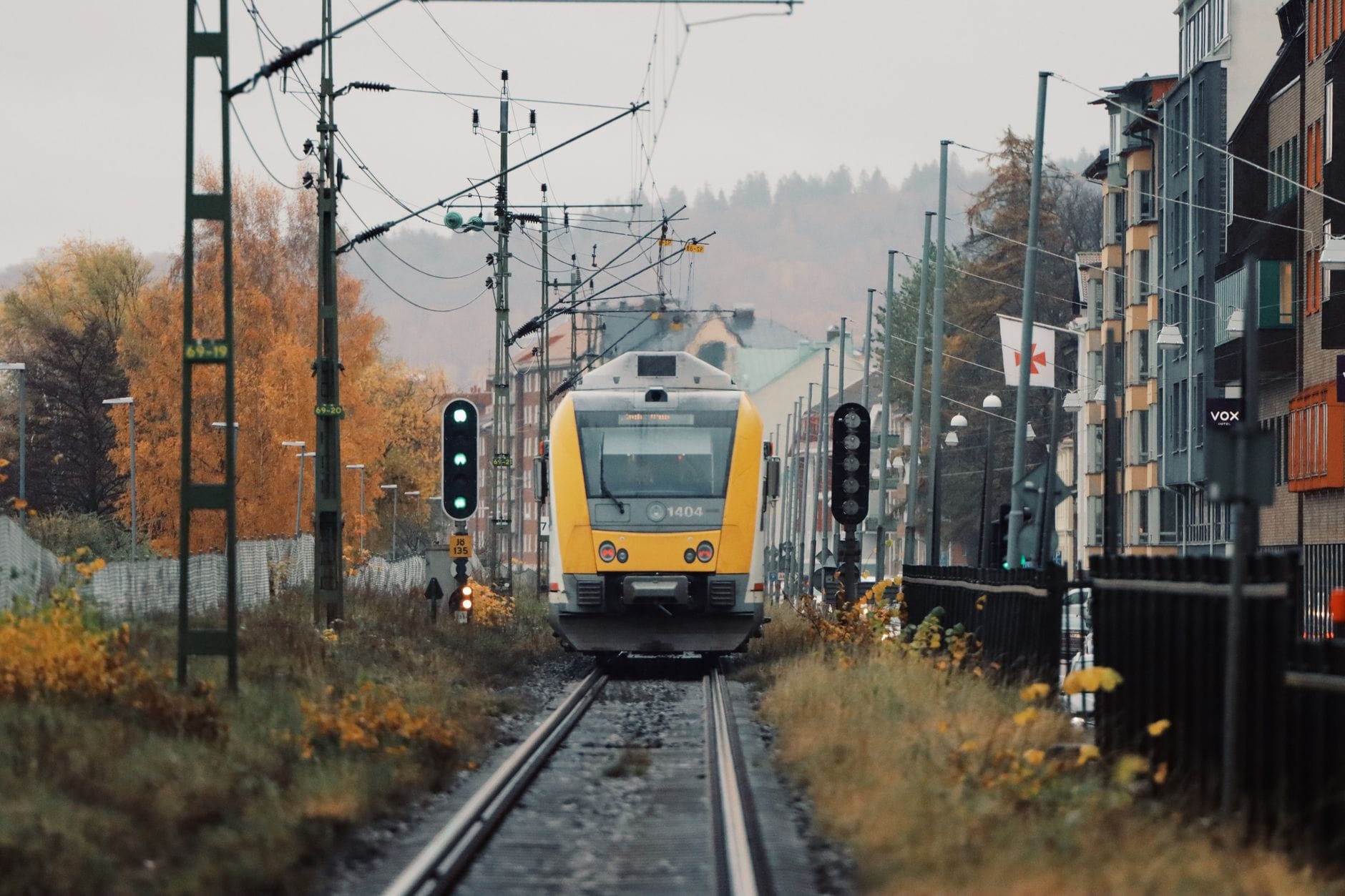 Żółty pociąg jedzie przez jesienne miasto Jönköping w Szwecji
